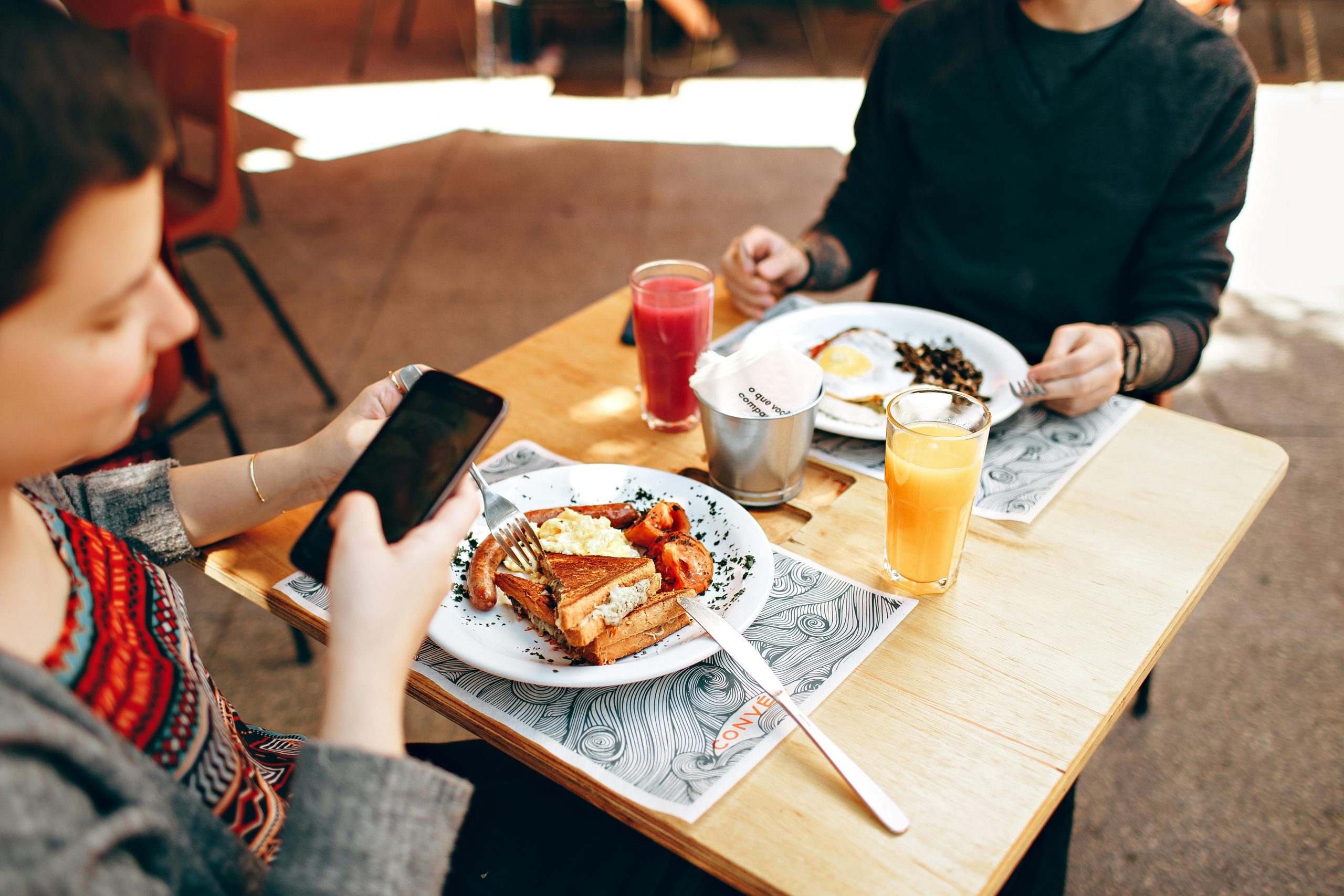 Two people enjoy brunch outdoors in Brazil, captured with a smartphone and Canon camera.