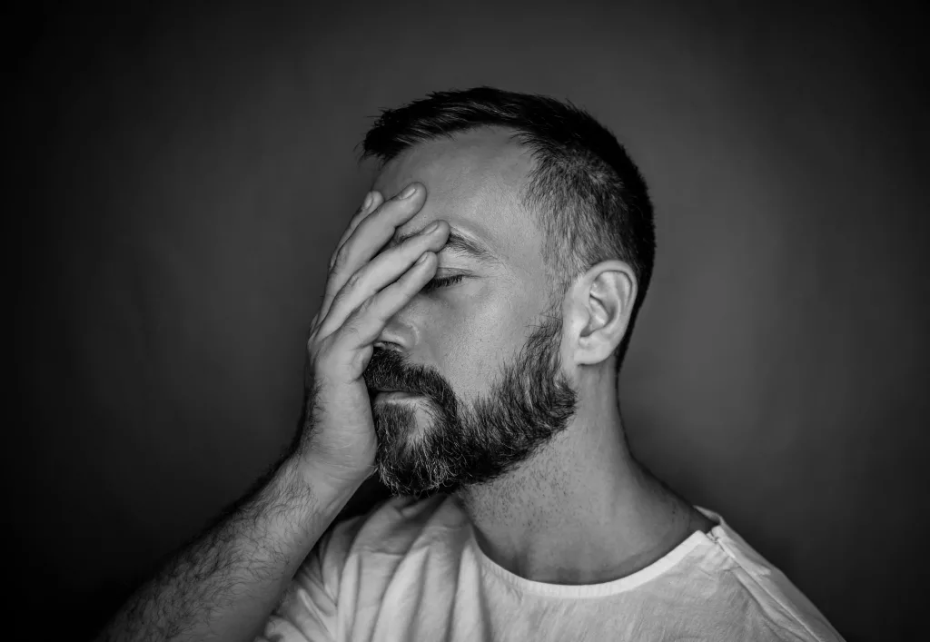 Expressive black and white portrait of a bearded man showing stress and contemplation.